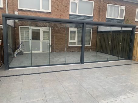 Moderne glazen veranda met een metalen frame en betegelde vloer.